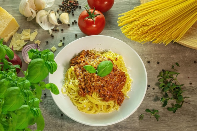 Pasta Bolognese mit Zutaten auf einem Holztisch