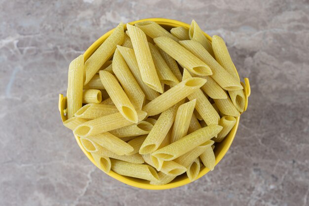 Pasta im gelben Eimer, auf der Marmoroberfläche.