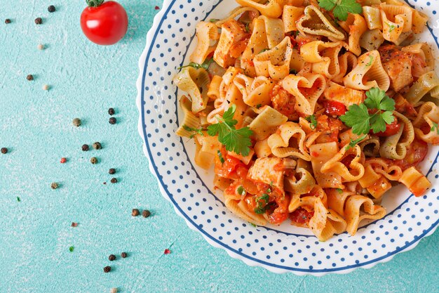 Pasta in Form von Herzen mit Huhn und Tomaten in Tomatensauce. Ansicht von oben