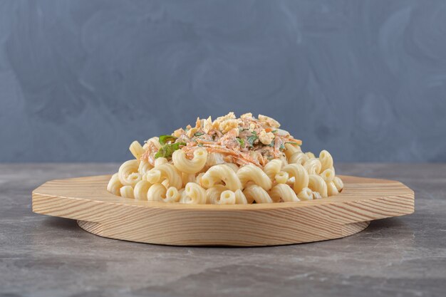 Pasta mit frischem Salat auf Holzplatte.