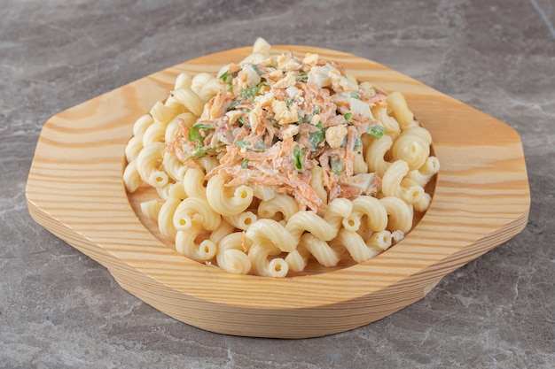 Pasta mit frischem Salat auf Holzplatte.