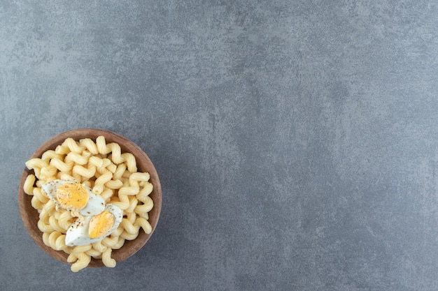 Pasta mit gekochten Eiern in Holzschale.