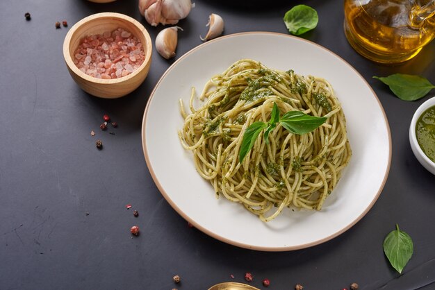 Pasta Spaghetti mit Zucchini, Basilikum, Sahne und Käse auf schwarzem Steintisch.