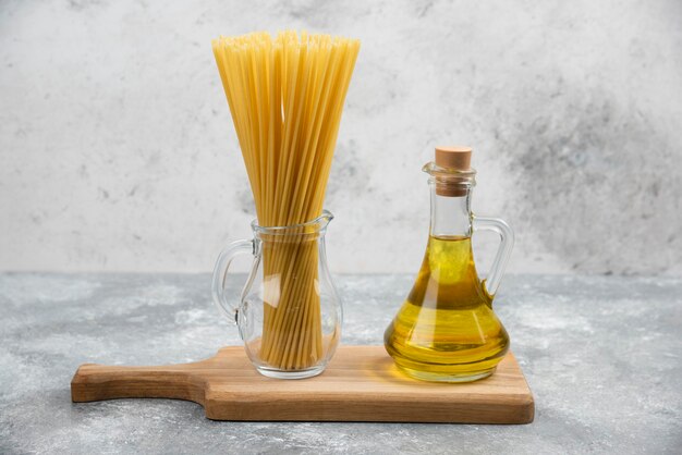 Pasta und eine Flasche Olivenöl extra vergine auf einem Holzbrett.