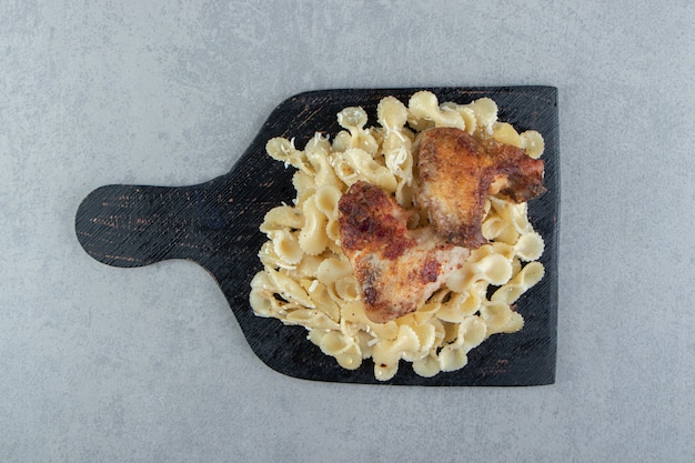 Pasta und gegrilltes Hähnchen auf schwarzem Brett.