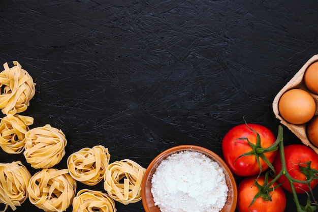 Pasta und Mehl in der Nähe von Tomaten und Eiern