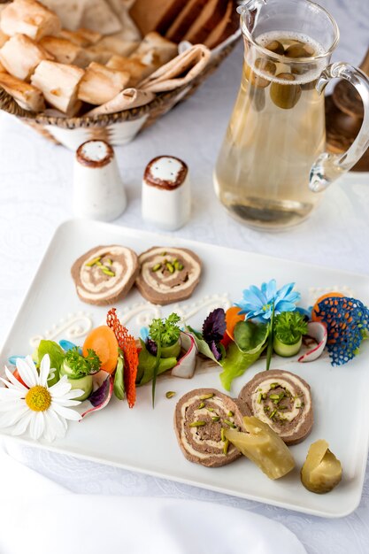 Pastete dekoriert mit Gurken und Karotten und einem Krug mit Kompott