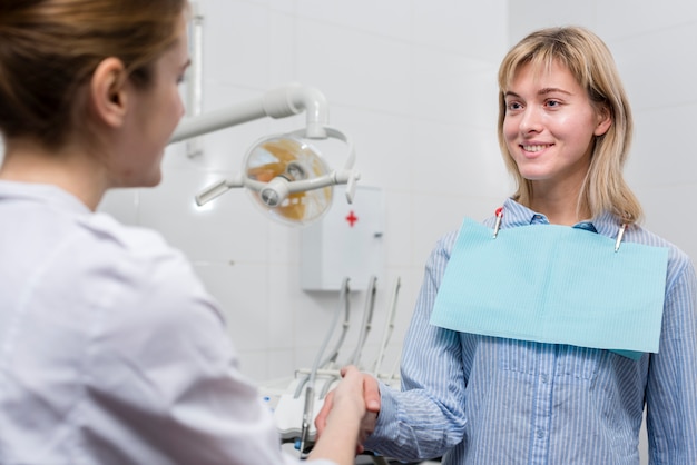 Patient, der Hand mit Zahnarzt rüttelt