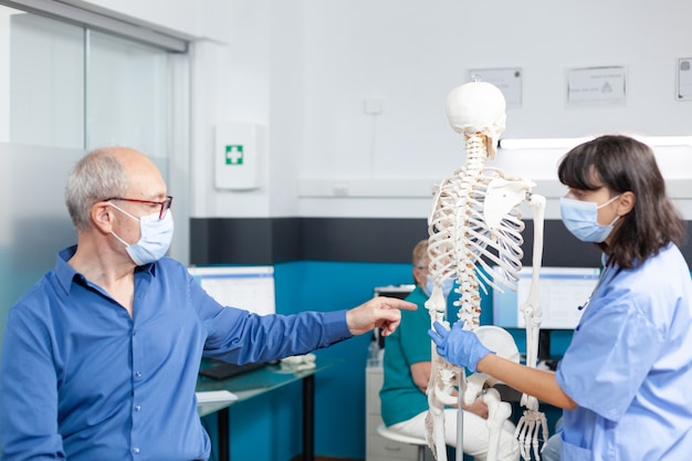 Patient und Krankenschwester mit Gesichtsmasken mit Blick auf die Wirbelsäulenknochen