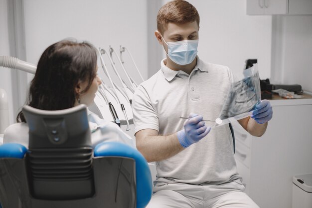 Patientin, die ihr Röntgenbild betrachtet. Stomatologe zeigt Bild der Mundhöhle