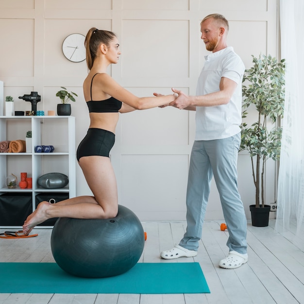 Kostenloses Foto patientin mit männlichem physiotherapeuten, der übungen mit ball macht