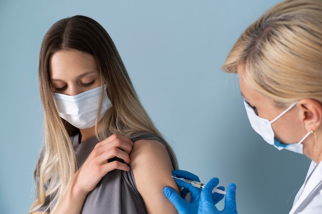 Kostenloses Foto patientin mit medizinischer maske, die einen impfstoff erhält