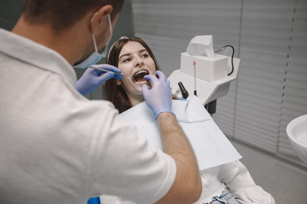 Patientin mit Zahnspange hat eine zahnärztliche Untersuchung in der Zahnarztpraxis. Frau in weißer Kleidung