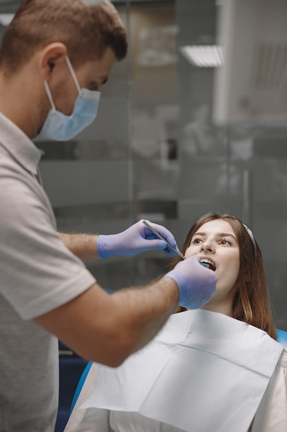 Patientin mit Zahnspange hat eine zahnärztliche Untersuchung in der Zahnarztpraxis. Stomatologe mit blauen Handschuhen