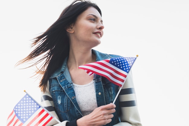 Patriotische Frau, die Flaggen von Amerika hält