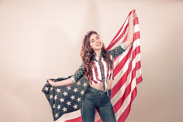 Patriotisches Mädchen mit der Flagge von Amerika auf einer farbigen Wand