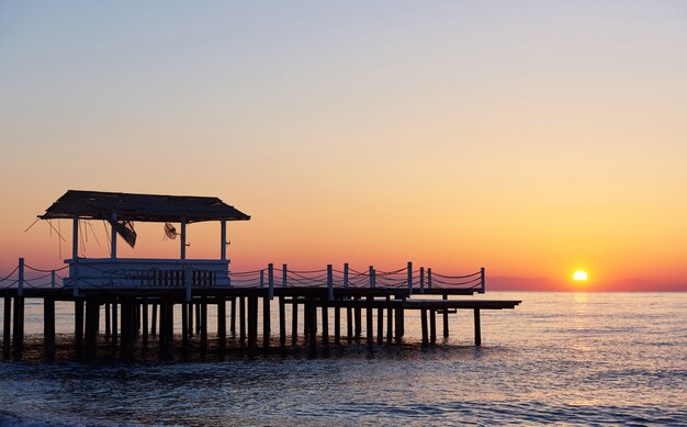 Pavillon auf dem hölzernen Pier ins Meer mit der Sonne bei Sonnenuntergang.
