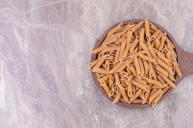 Penne Pasta auf einer Holzplatte auf dem Marmor