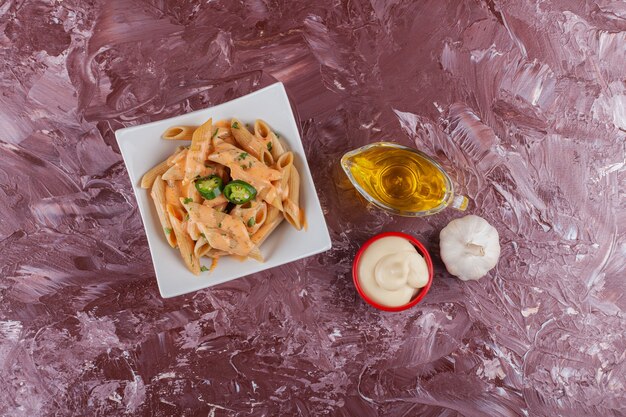 Penne pasta mit mayonnaise und frischem knoblauch auf einem leuchttisch.