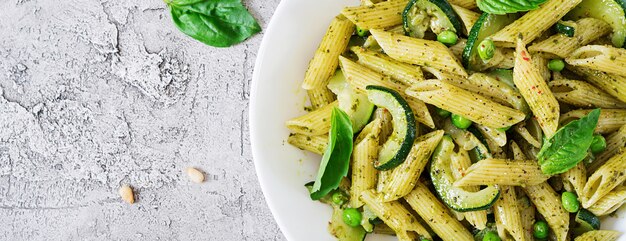 Penne Pasta mit Pesto-Sauce, Zucchini, Erbsen und Basilikum. Italienisches Essen. Draufsicht. Flach liegen.