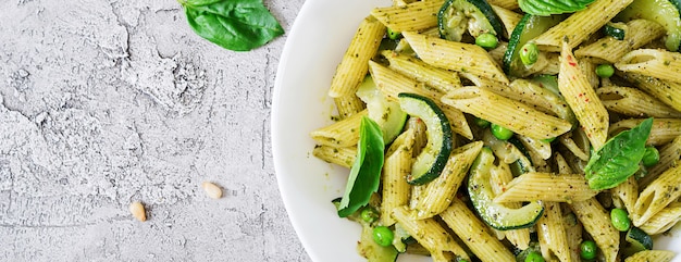 Penne Pasta mit Pesto-Sauce, Zucchini, Erbsen und Basilikum. Italienisches Essen. Draufsicht. Flach liegen.