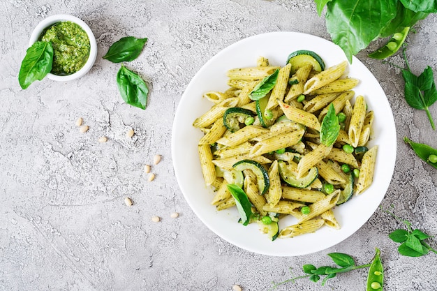 Penne Pasta mit Pesto-Sauce, Zucchini, Erbsen und Basilikum. Italienisches Essen. Draufsicht. Flach liegen.