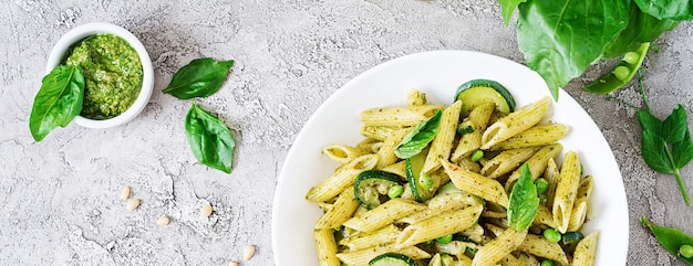 Penne Pasta mit Pesto-Sauce, Zucchini, Erbsen und Basilikum. Italienisches Essen. Draufsicht. Flach liegen.