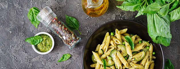 Penne Pasta mit Pesto-Sauce, Zucchini, Erbsen und Basilikum. Italienisches Essen. Draufsicht. Flach liegen.