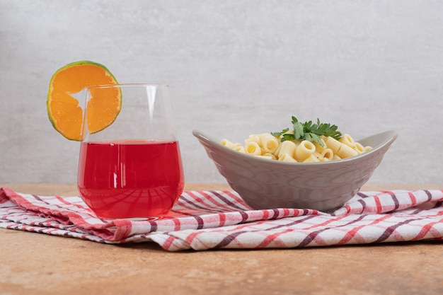 Penne Pasta und Glas roter Cocktail auf Tischdecke