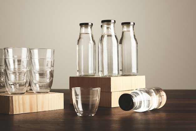 Perfektes Set aus reinem, sauberem, gesundem Wasser in transparenten Glasflaschen und Tassen auf Holz