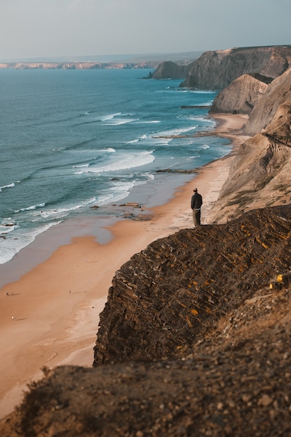 Person auf einer Klippe, die den schönen Ozean in Algarve, Portugal betrachtet