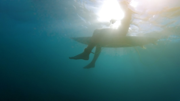 Person, die auf Surfbrett im blauen Meer sitzt