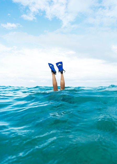 Person, die Beine hoch hält, während sie im Ozean schwimmt und Flossen trägt