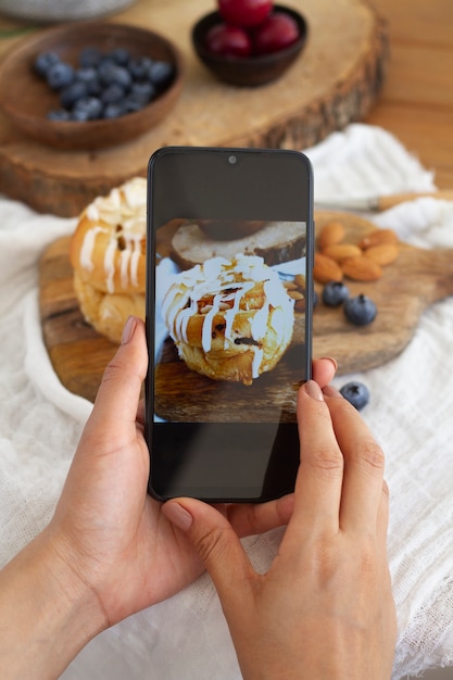 Person, die Blätterteig mit Topping mit ihrem Smartphone fotografiert