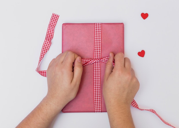 Person, die Bogen auf rosa Geschenkbox bindet