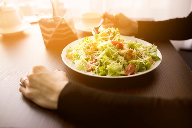 Person, die Caesar Salad mit Garnele im Restaurant isst