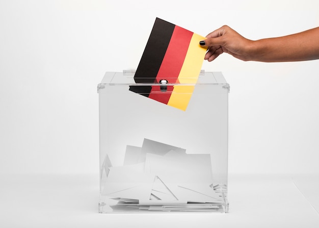 Kostenloses Foto person, die deutschland-flaggenkarte in wahlurne setzt