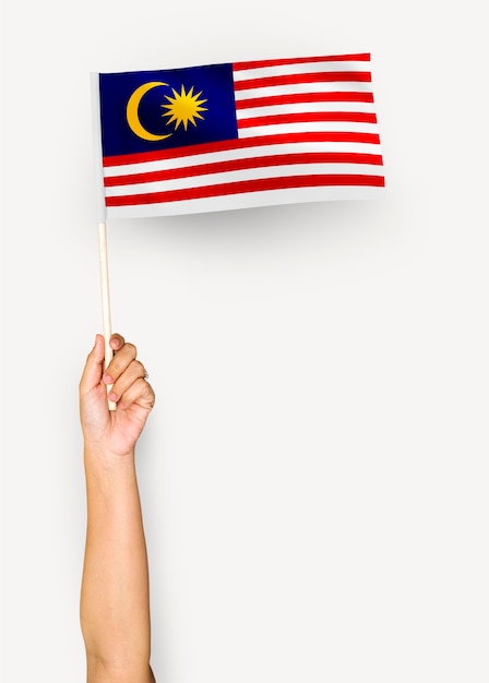 Person, die die Flagge von Malaysia wellenartig bewegt