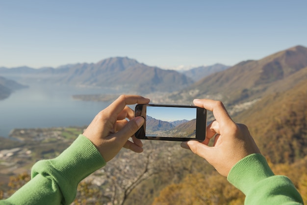 Kostenloses Foto person, die ein foto des maggiore-alpensees und der berge in der schweiz macht