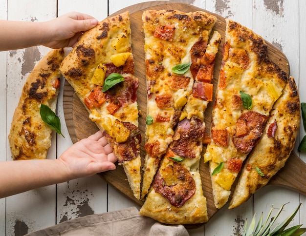 Kostenloses Foto person, die ein großes stück köstliche gekochte pizza greift