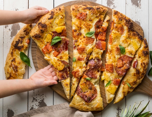 Person, die ein großes Stück köstliche gekochte Pizza greift