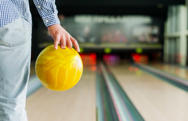 Person, die eine gelbe Bowlingkugel hält