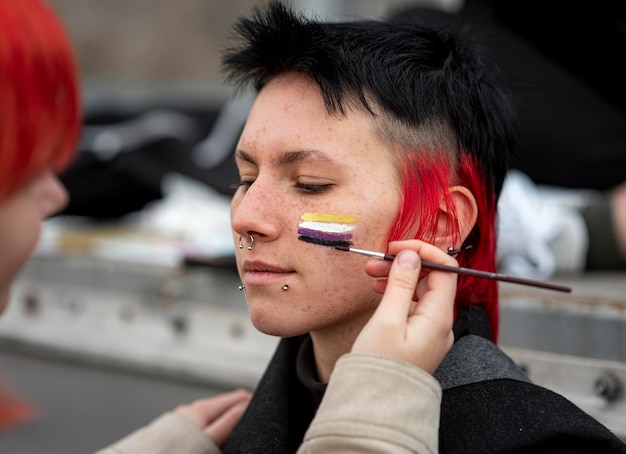 Kostenloses Foto person, die eine nicht-binäre flagge auf eine freund-nahaufnahme malt