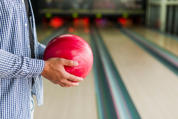 Person, die eine rote Bowlingkugel hält