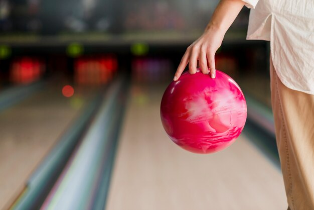 Person, die eine rote Bowlingkugel hält