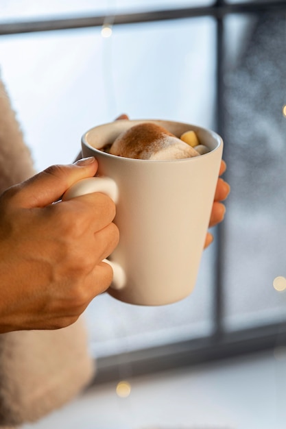 Person, die eine weiße Tasse heiße Schokolade hält