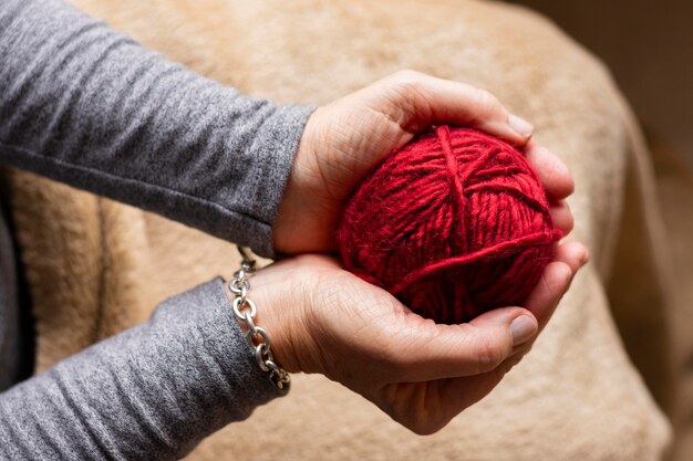 Person, die einen roten Faden zum Stricken hält