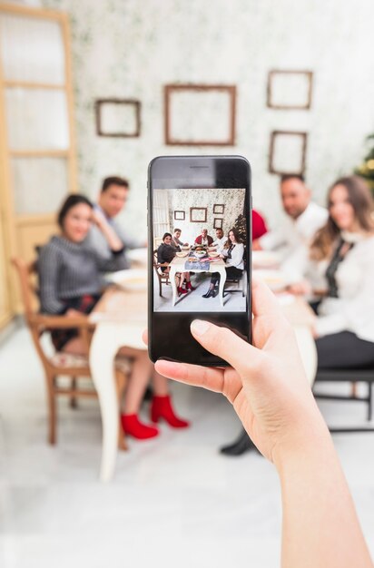 Person, die Foto der glücklichen Familie am festlichen Tisch macht