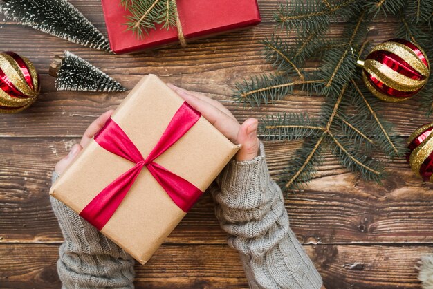 Person, die Geschenkbox auf Tabelle hält