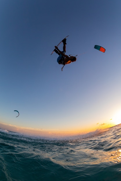 Person, die gleichzeitig beim Kitesurfen surft und einen Fallschirm fliegt